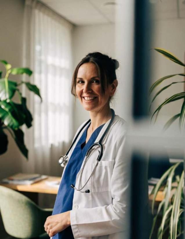 Smiling GP standing in a bright private consulting room