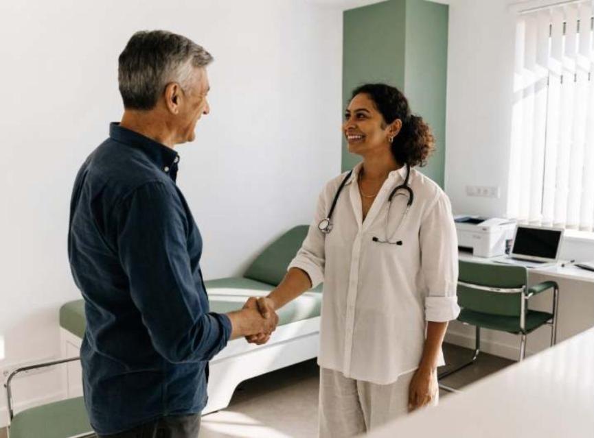 GP welcoming a patient into a bright consulting room